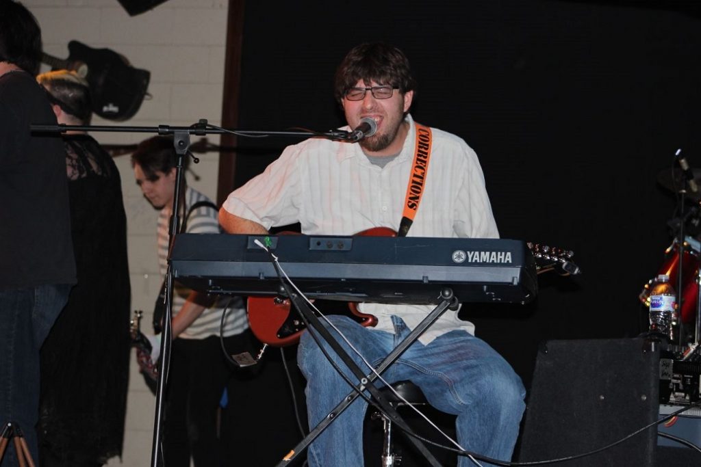 Picture of Mark playing keyboard and guitar.
